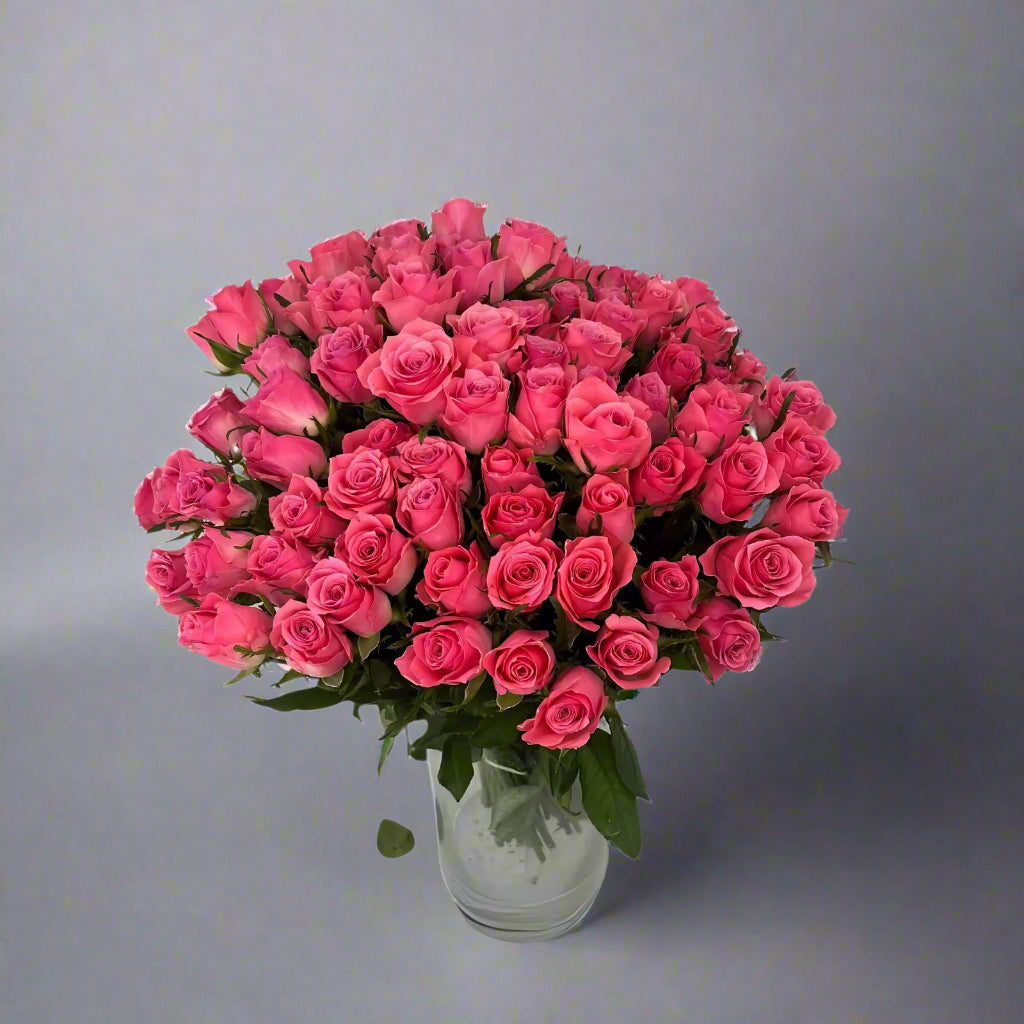 Bouquet of pink roses in a clear vase on a white background