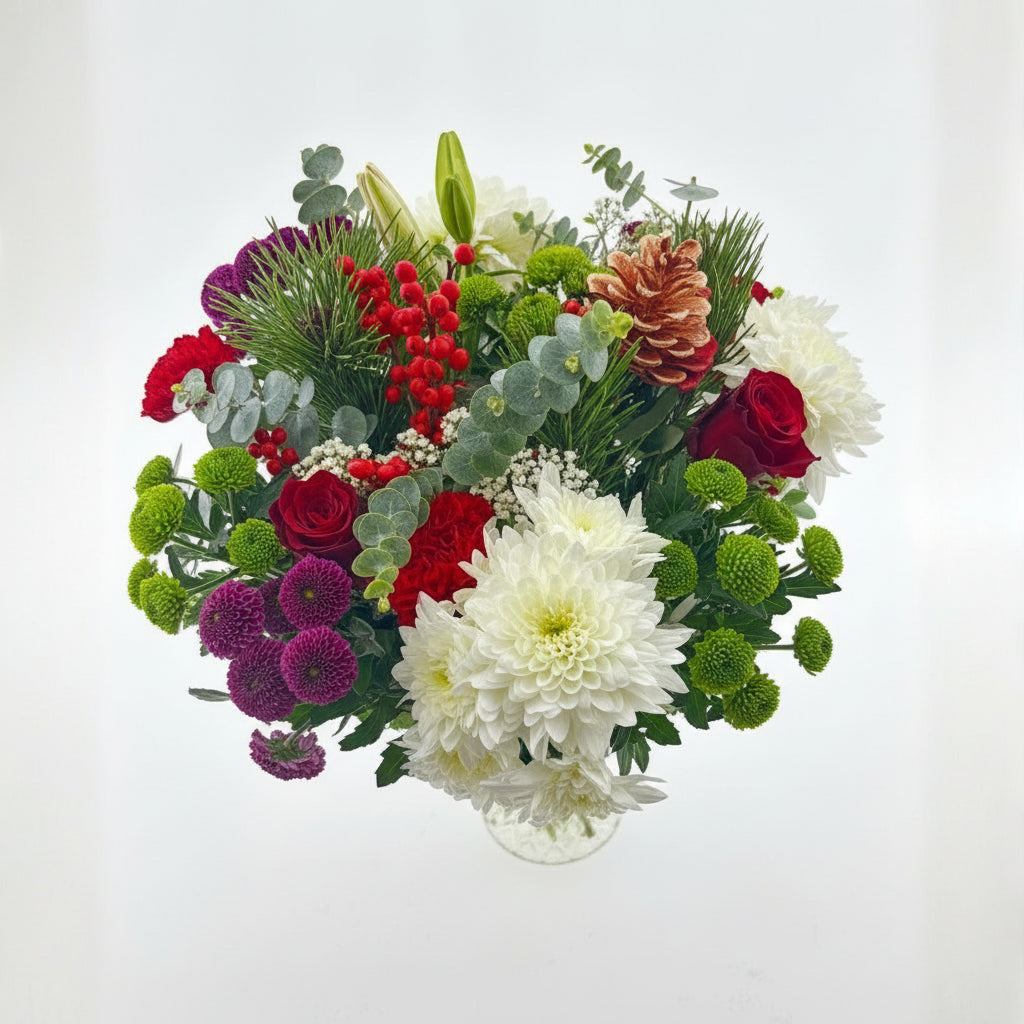 Colorful Christmas bouquet of flowers including red roses, greenery, and white flowers on a light gray background