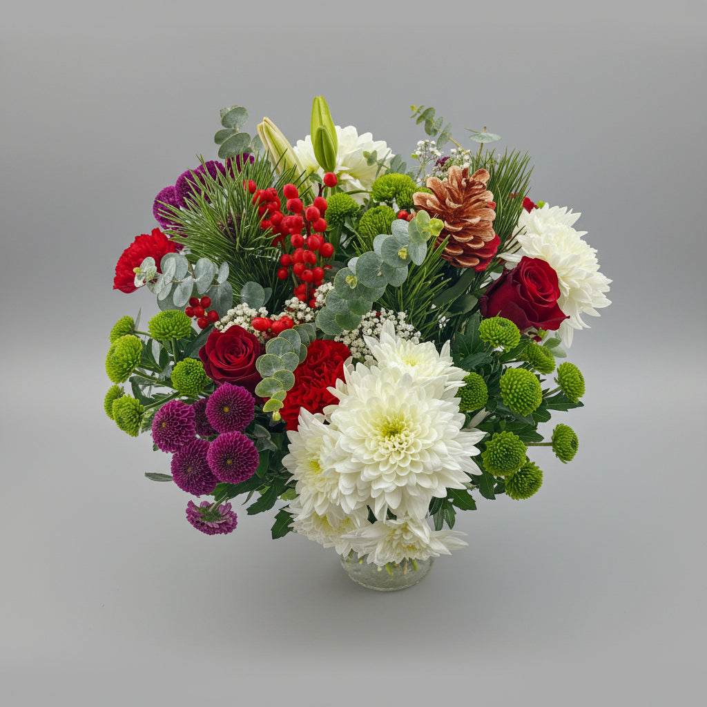 Colorful Christmas bouquet of flowers including red roses, greenery, and white flowers on a light gray background