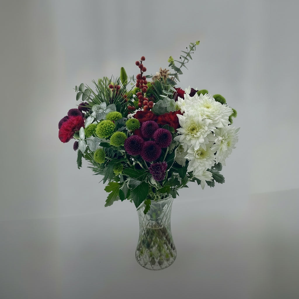 Bouquet of flowers in a clear vase on a light gray background