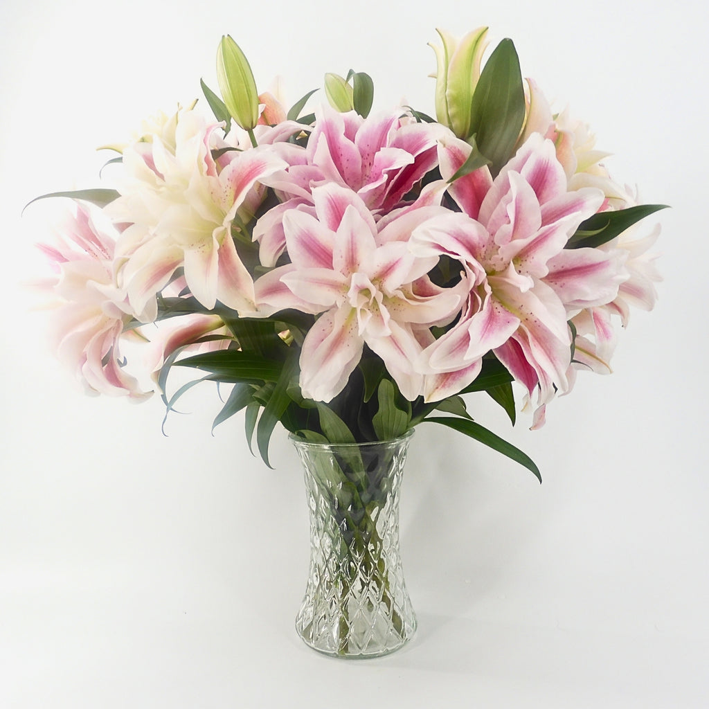 Rose lilies bouquet in a glass vase from a lower angle