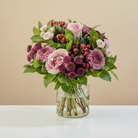 Bouquet of flowers in a clear vase on a light surface with a beige background