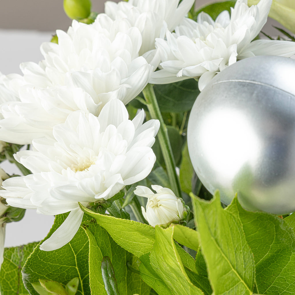 Close up view of white flowers and bauble from Christmas white roses bouquet with white wine bottle