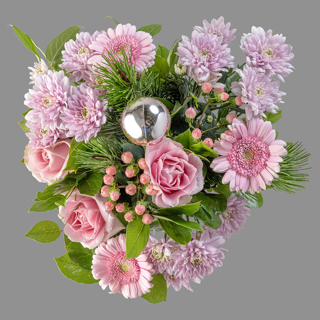 Top down view of Christmas pink roses bouquet in a glass vase with organic white wine
