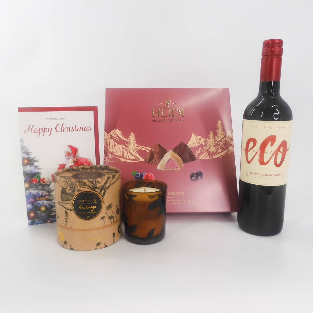 A luxurious Christmas gift set complete with a bottle of Eco red wine, Heidi Swiss Chocolate selection, a lovely scented candle and friendly Happy Christmas card from a lower angle