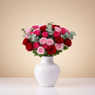 Bouquet of red and pink roses in a white vase on a light background