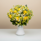 Bouquet of yellow flowers in a white vase on a beige background