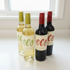 Two bottles of white wine and two bottles of red wine with 'eco' labels on a light surface.
