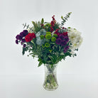 Christmas Special Bouquet of flowers in a clear vase on a light gray background
