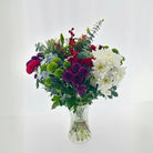 Bouquet of flowers in a clear vase on a light gray background