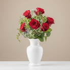Bouquet of red roses with greenery in a white vase on a beige background