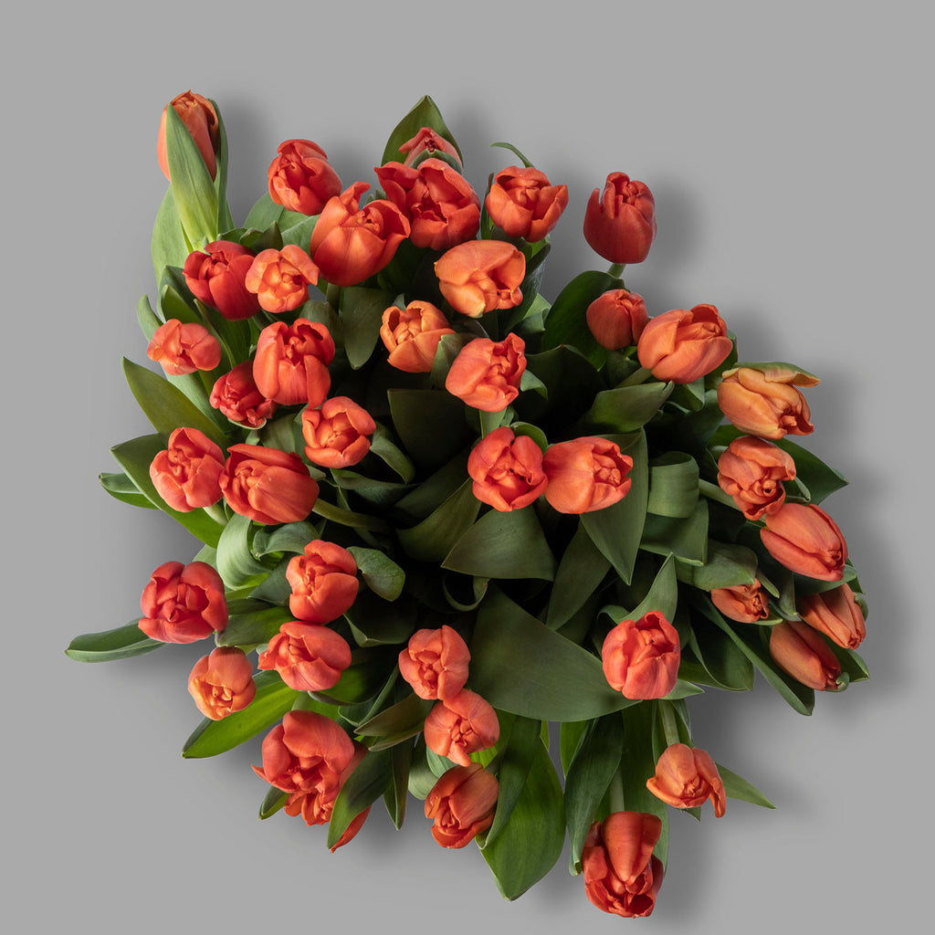 Top down view of Christmas orange tulips bouquet with chocolates and a Christmas card