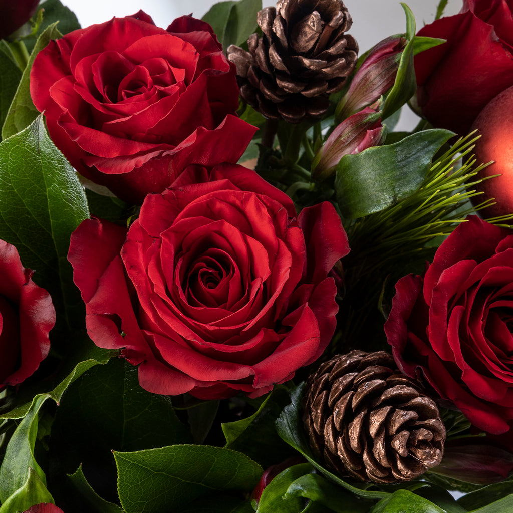 Close up view of a roses and pinecone from Red roses christmas bliss flower bouquet with baubles