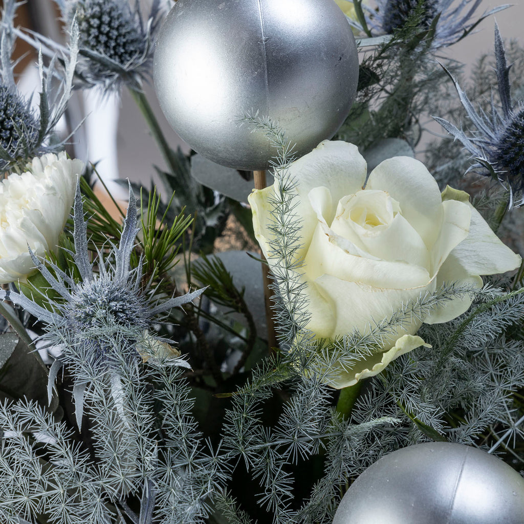 Close up view of a white rose from White roses christmas frosty flower bouquet with baubles