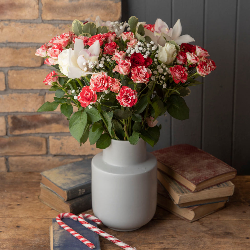 Lifestyle picture of Christmas Sparkle flower bouquet with speckled red and white roses