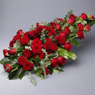 Red rose funeral spray with green floral elements