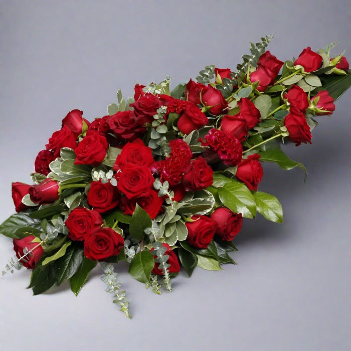 Red rose funeral spray with green floral elements