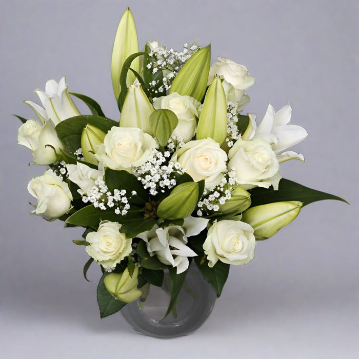 Rose and white lily bouquet in a glass vase